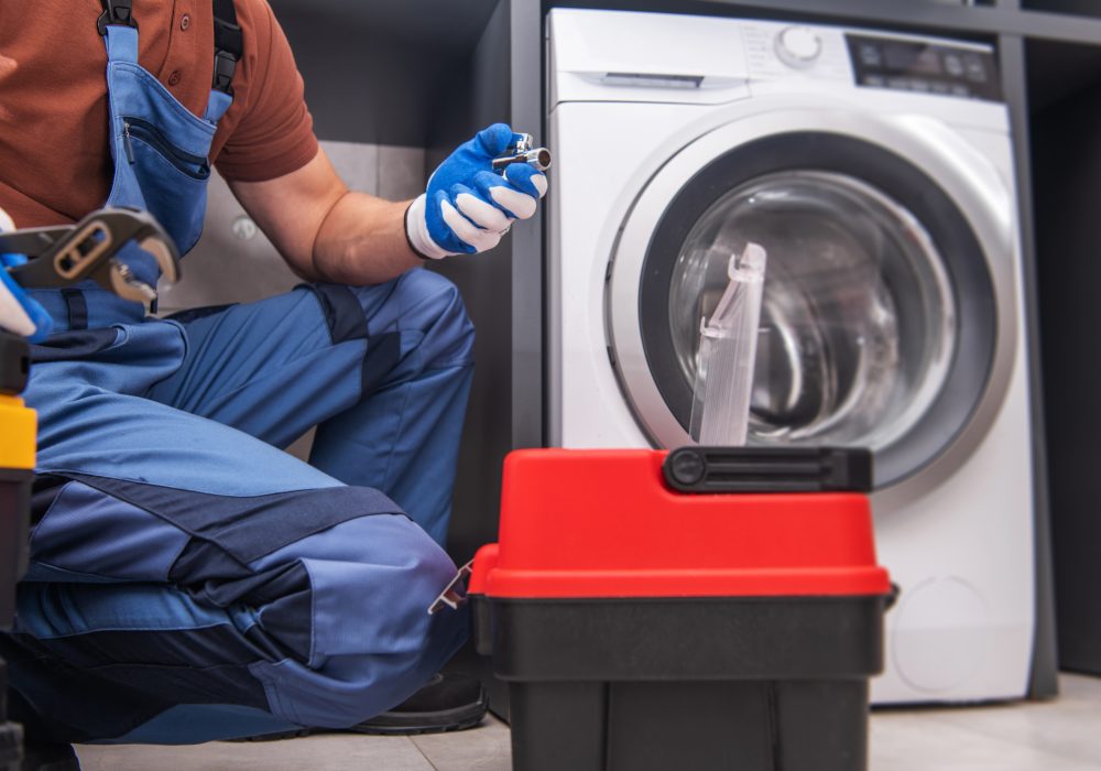 Caucasian Professional Worker Installing Washing Machine Inside Residential Apartment.